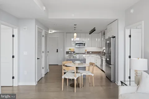 a dining room with stainless steel appliances kitchen island granite countertop furniture and a refrigerator