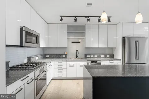 a kitchen with stainless steel appliances granite countertop a sink stove and refrigerator