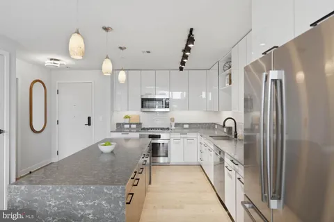 a kitchen with kitchen island granite countertop a sink a stove and refrigerator
