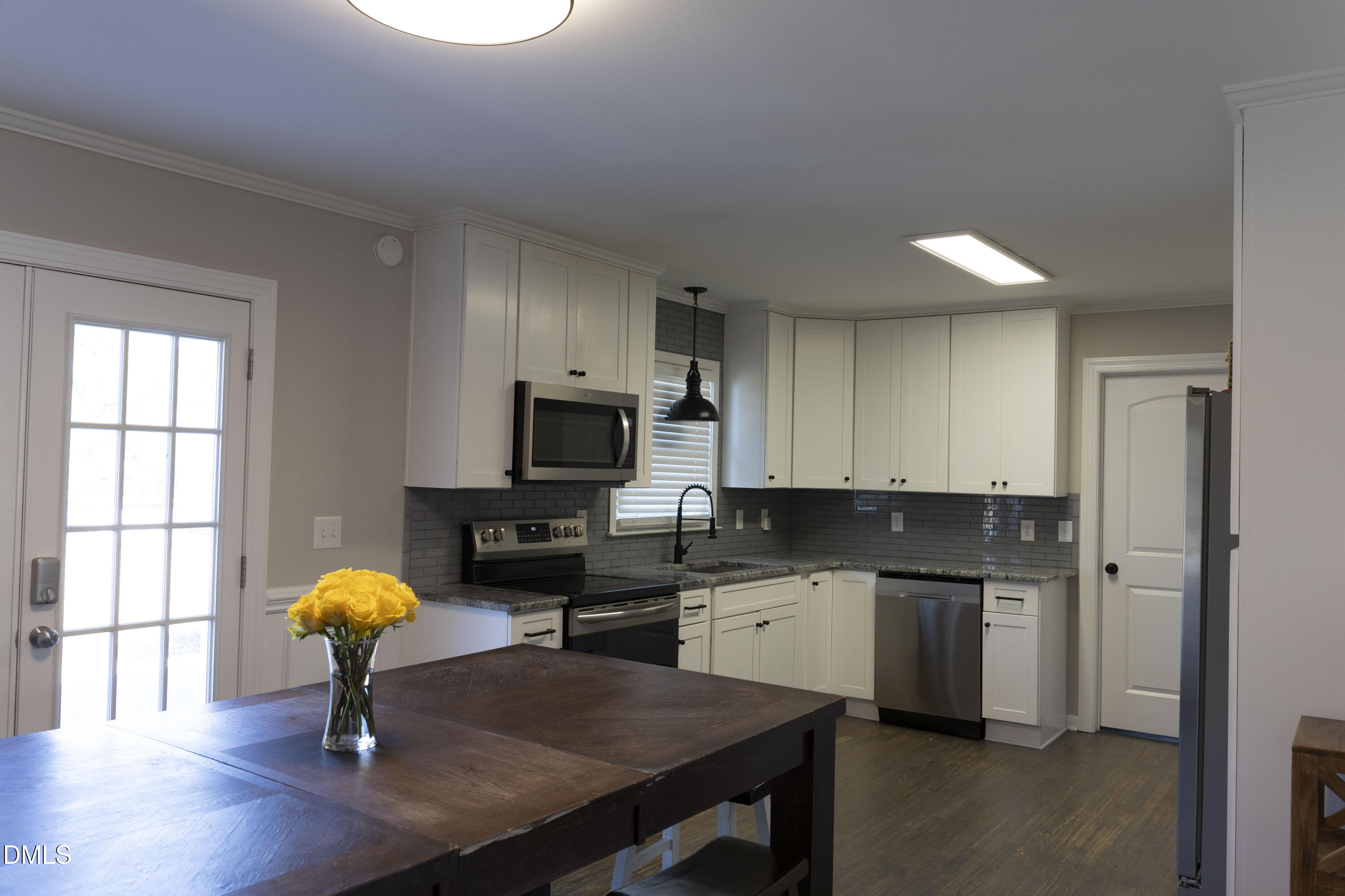 7301 Cleveland School Road Garner, NC 27529 - Photo 9 of 73 a kitchen with stainless steel appliances granite countertop a sink dishwasher a stove a refrigerator a dining table and chairs with wooden floor