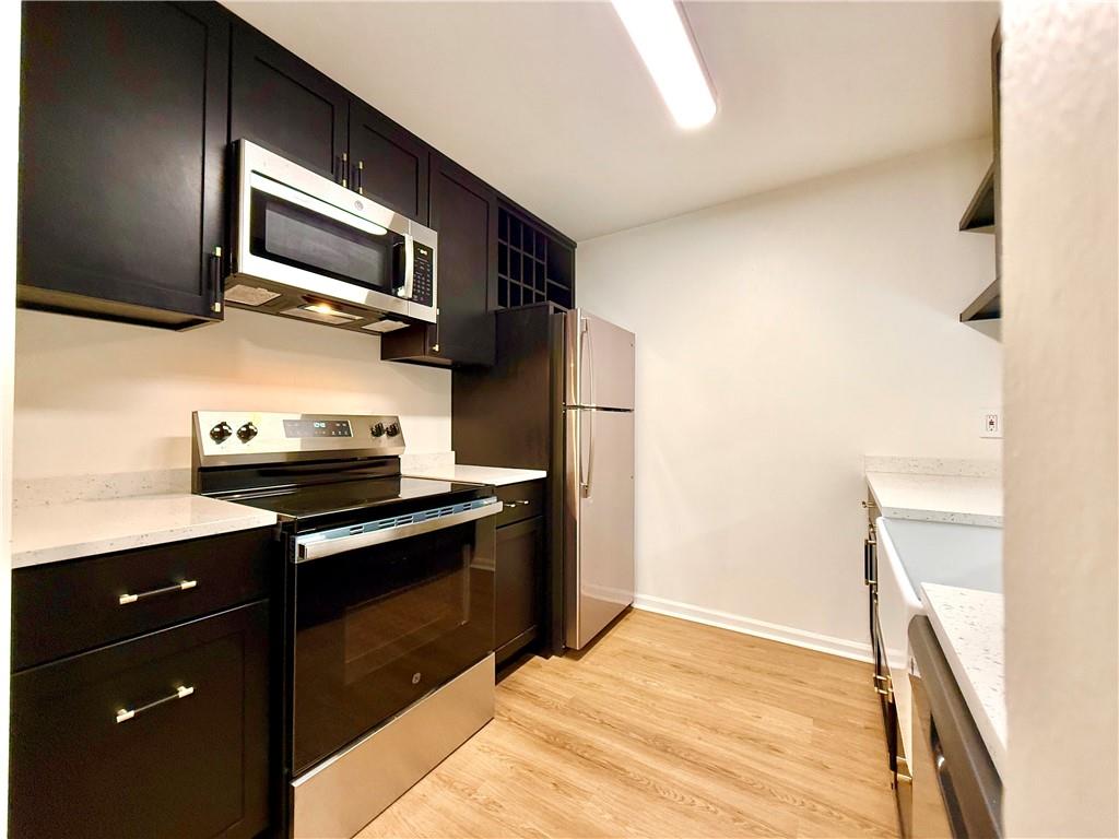 3655 Habersham Road Northeast, Unit A212 Atlanta, GA 30305 - Photo 5 of 21 a kitchen with stainless steel appliances granite countertop a stove a microwave and a refrigerator