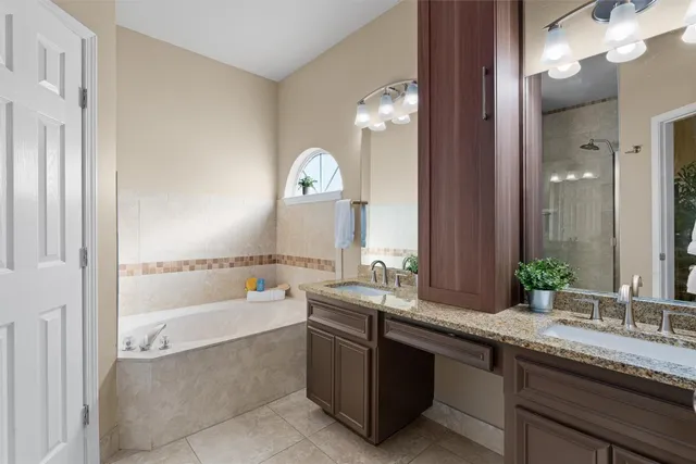 a bathroom with a bathtub a double vanity sink and mirror