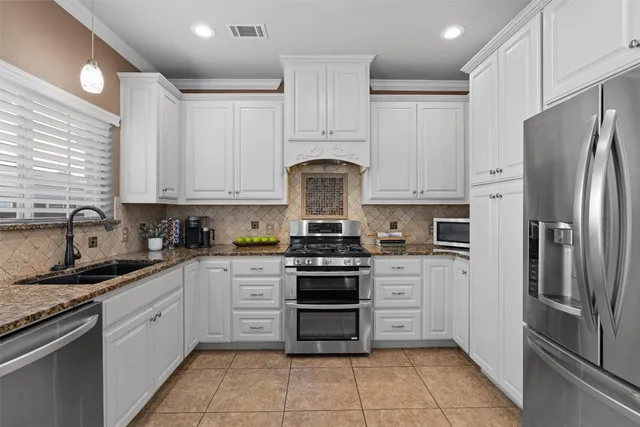 a kitchen with stainless steel appliances granite countertop a stove a refrigerator and a sink