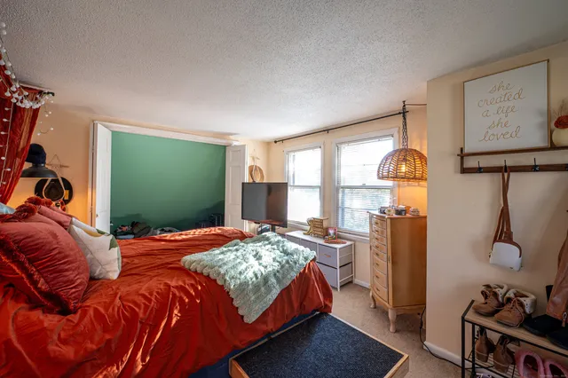 a bedroom with bed and a flat tv screen on the dresser