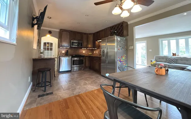 a kitchen with refrigerator a sink dishwasher a dining table and chairs with wooden floor