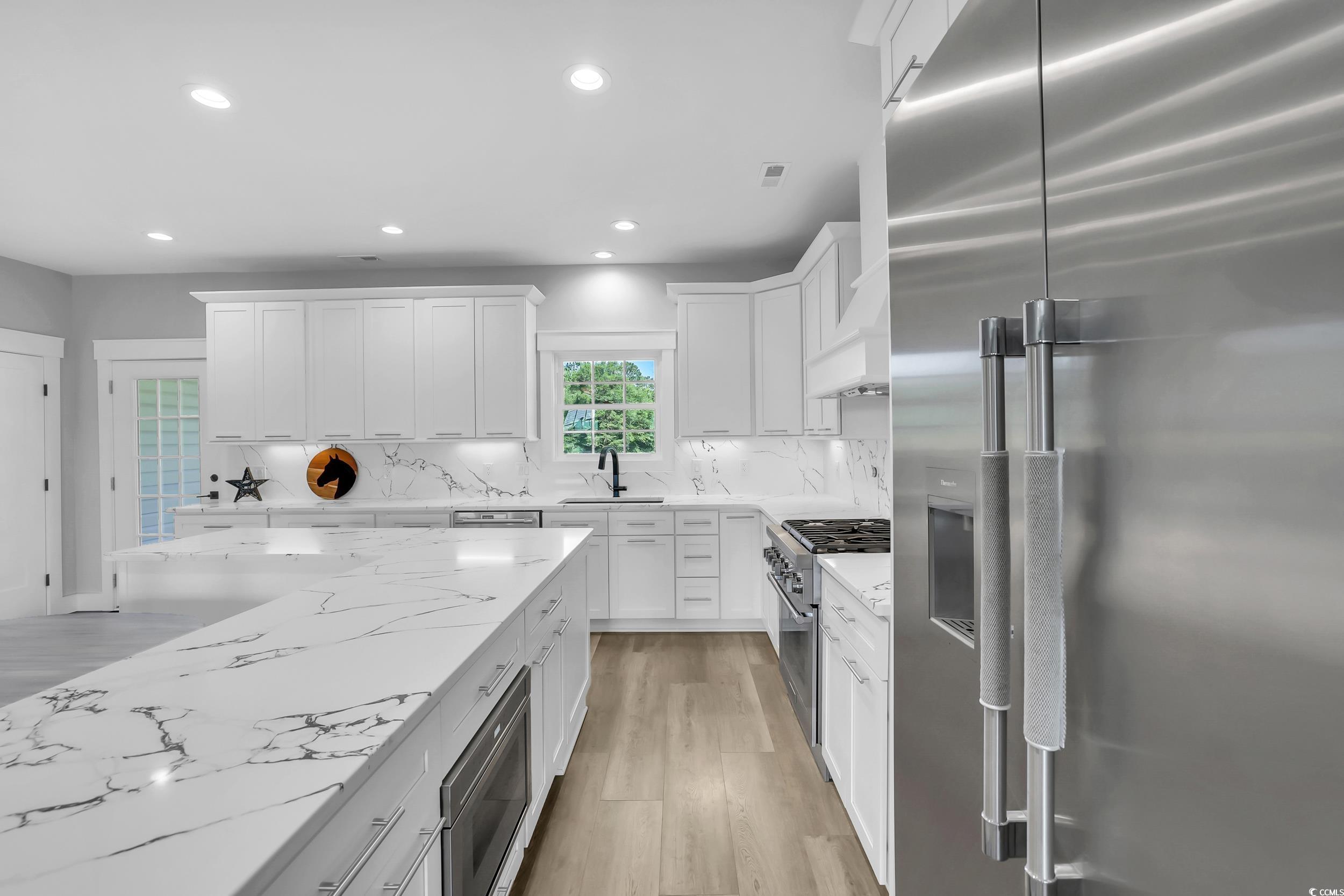 7356 Johnson Shortcut Road Conway, SC 29527 - Photo 16 of 40 Kitchen featuring high end appliances, light wood-type flooring, recessed lighting, white cabinetry, and tasteful backsplash