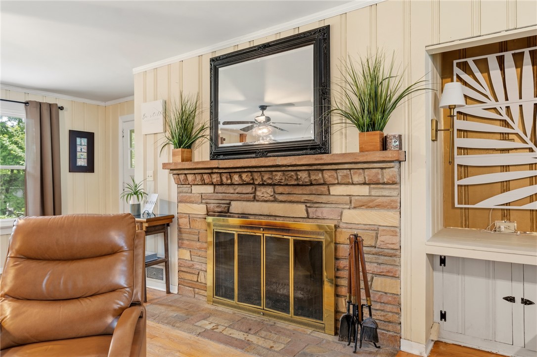1105 Greenacres Anderson, SC 29621 - Photo 9 of 46 A stone fireplace with a rustic wood mantel creates a cozy focal point for the living space.