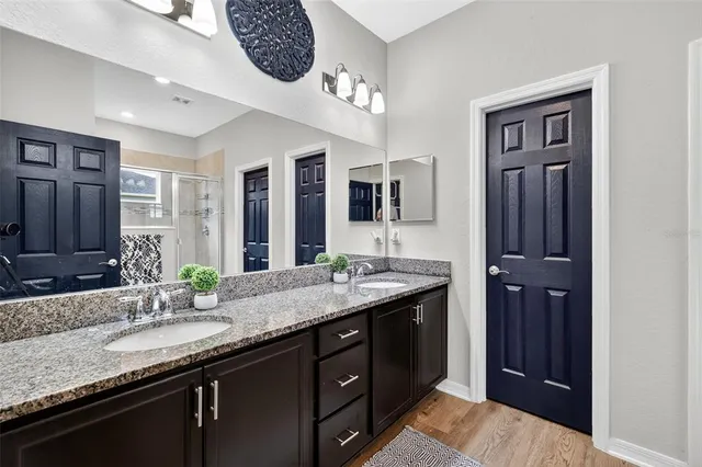 a bathroom with a granite countertop double vanity sink and a mirror