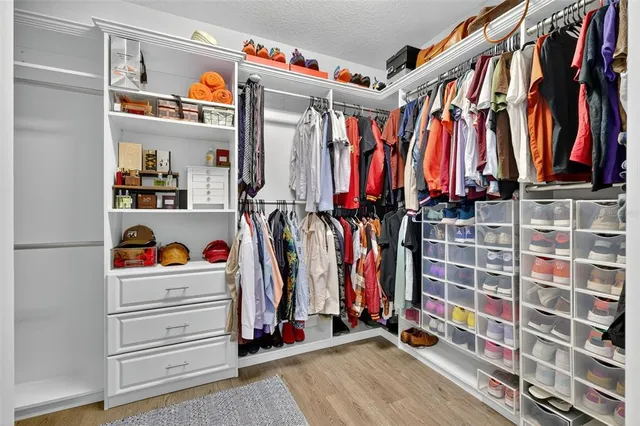 a view of walk in closet with clothes and shoes