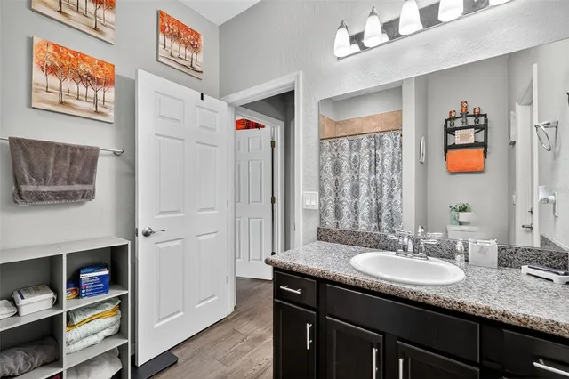 a bathroom with a granite countertop sink a mirror and a shower
