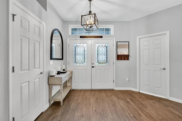 a view of a livingroom with a chandelier wooden floor and windows