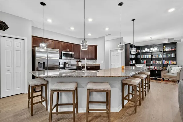 a kitchen with stainless steel appliances granite countertop a stove a refrigerator a kitchen island a dining table and chairs