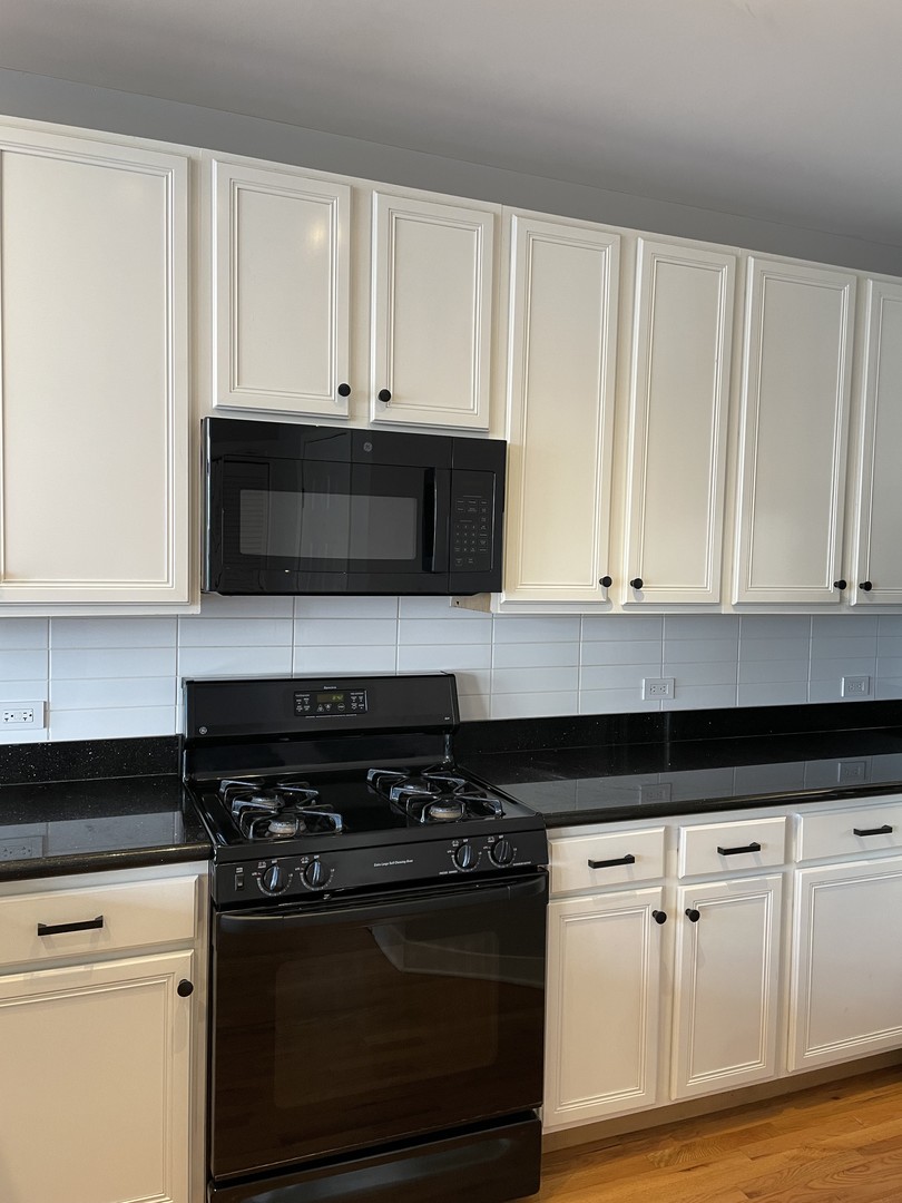 849 West Monroe Street, Unit 3F Chicago, IL 60607 - Photo 5 of 18 a kitchen with stainless steel appliances granite countertop white cabinets and black stove top oven with granite countertops