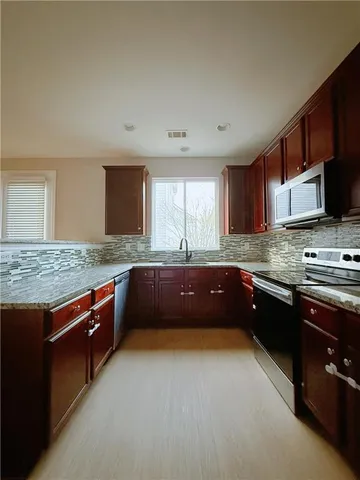 a kitchen with stainless steel appliances granite countertop wooden cabinets a stove top oven a granite counter tops and a sink