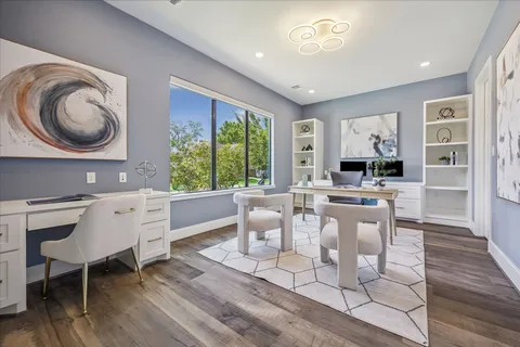 a living room with furniture a large window and wooden floor