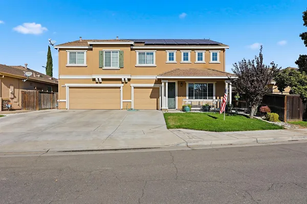a front view of a house with a yard and potted plants