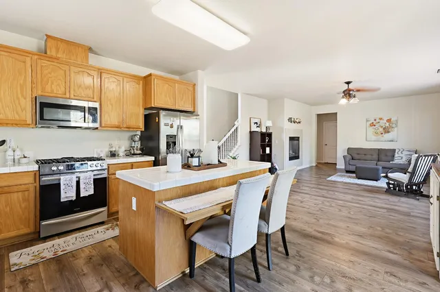 a kitchen with stainless steel appliances a stove a sink dishwasher a oven with a dining table and chairs