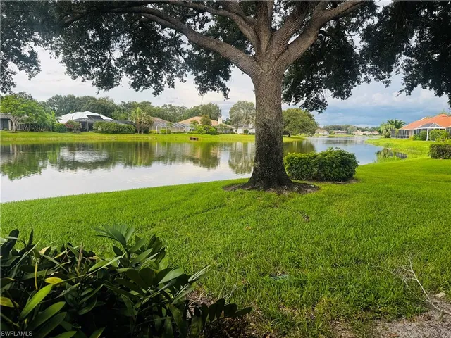 a view of a lake with a big yard and large trees