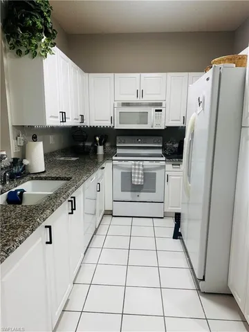 a kitchen with granite countertop a refrigerator a stove a sink a microwave and cabinets