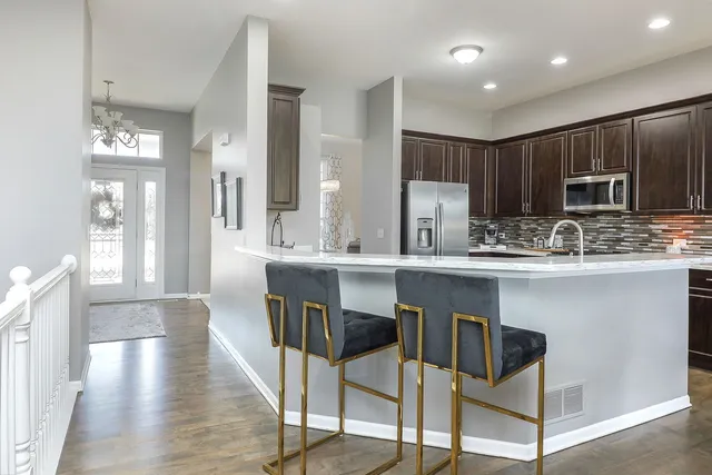 a kitchen with kitchen island granite countertop wooden floors cabinets and stainless steel appliances