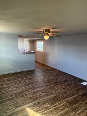 a view of empty room with wooden floor and window