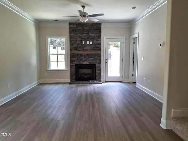 an empty room with wooden floor fireplace and windows