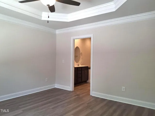 a view of an empty room with wooden floor and a ceiling fan