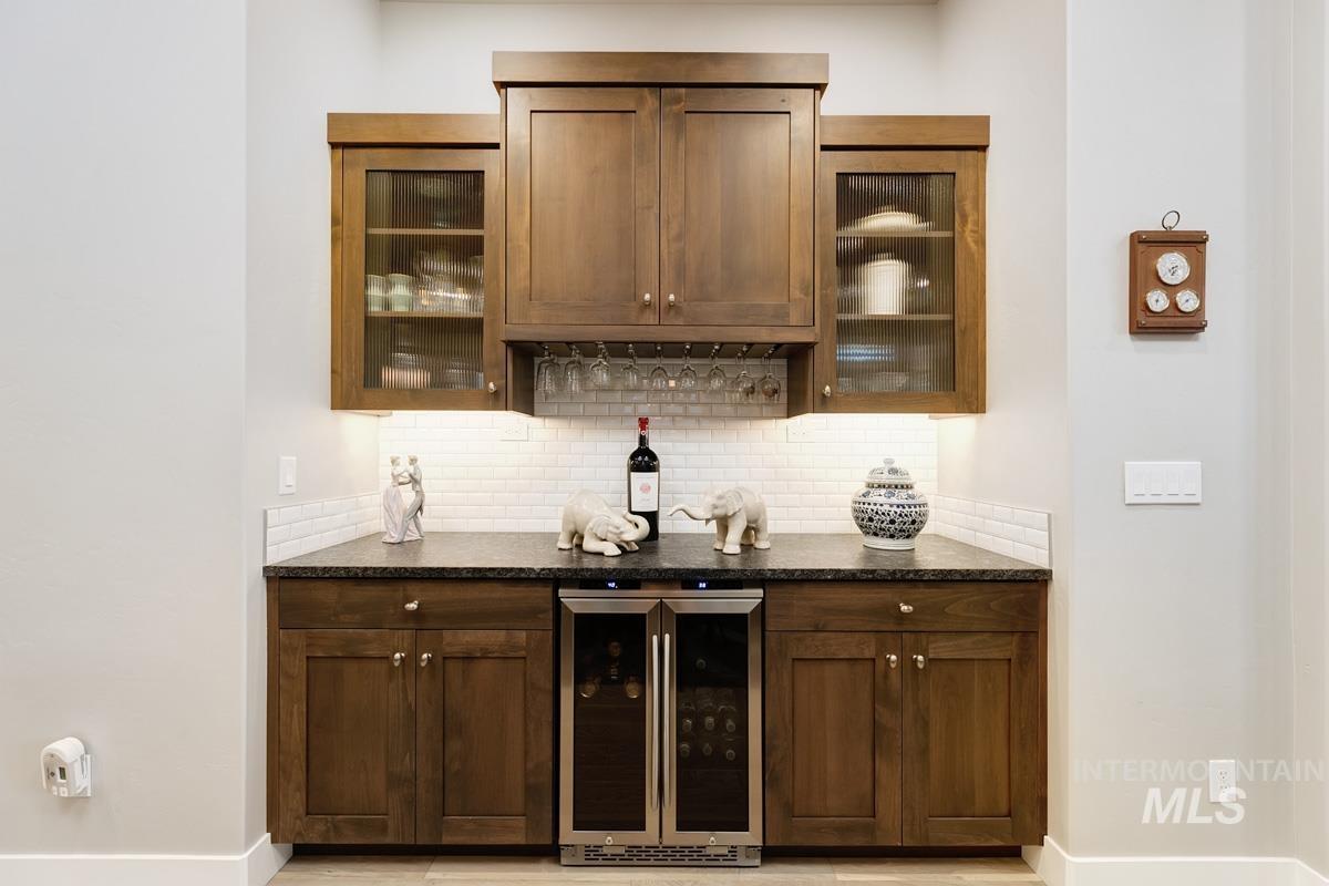 410 West Lockhart Lane Meridian, ID 83646 - Photo 13 of 41 Bar area featuring beverage cooler, glass insert cabinets, and dark stone countertops