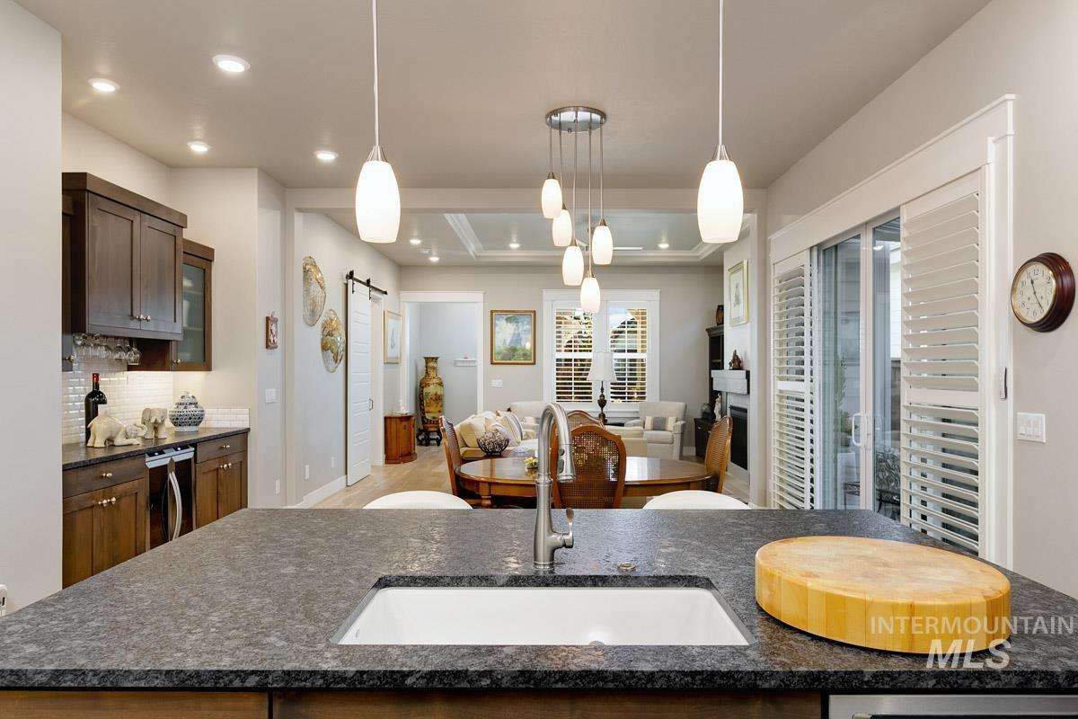410 West Lockhart Lane Meridian, ID 83646 - Photo 41 of 41 Kitchen with a barn door, hanging light fixtures, dark stone counters, open floor plan, and a center island with sink