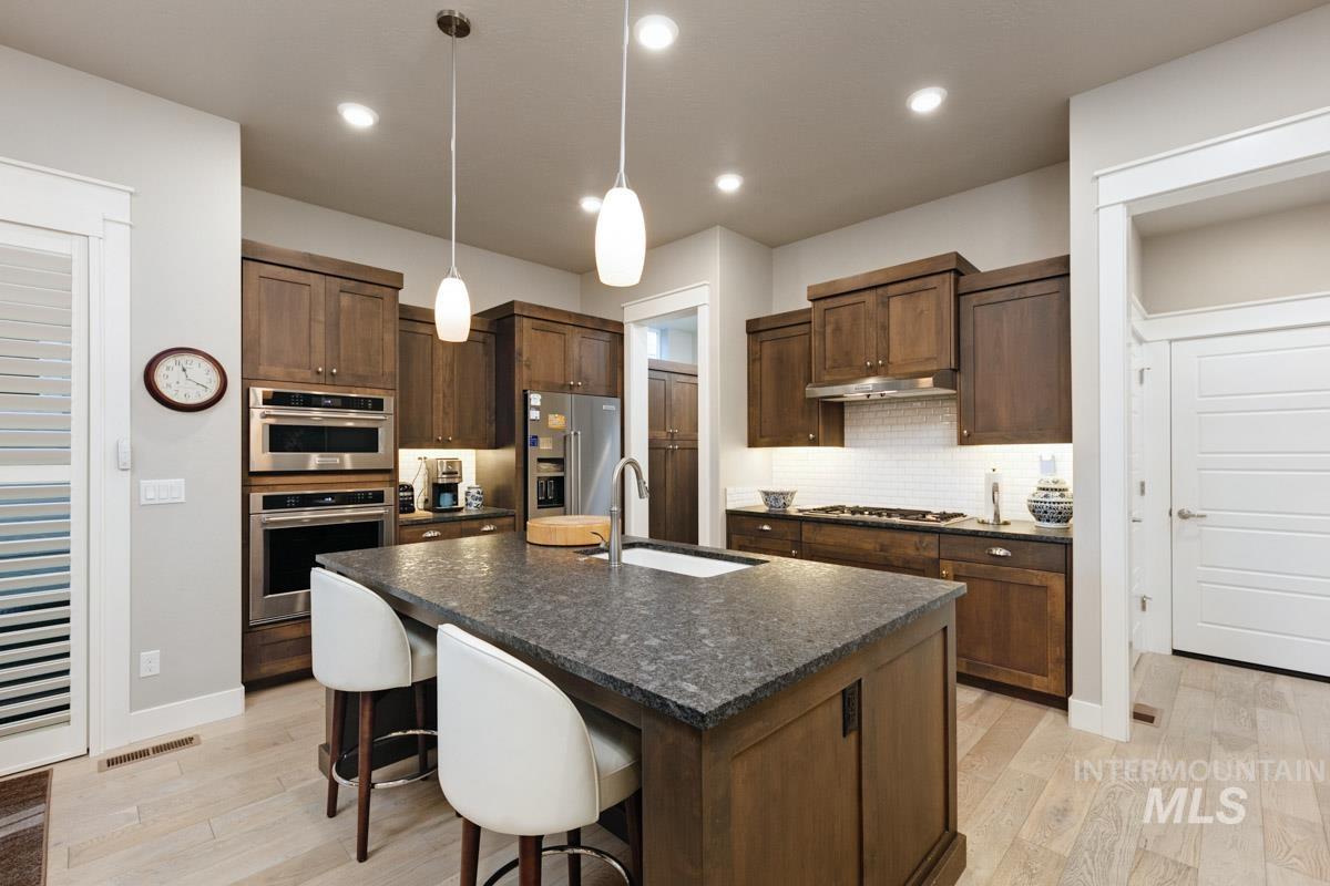 410 West Lockhart Lane Meridian, ID 83646 - Photo 14 of 41 Kitchen with a kitchen bar, hanging light fixtures, light wood finished floors, and an island with sink