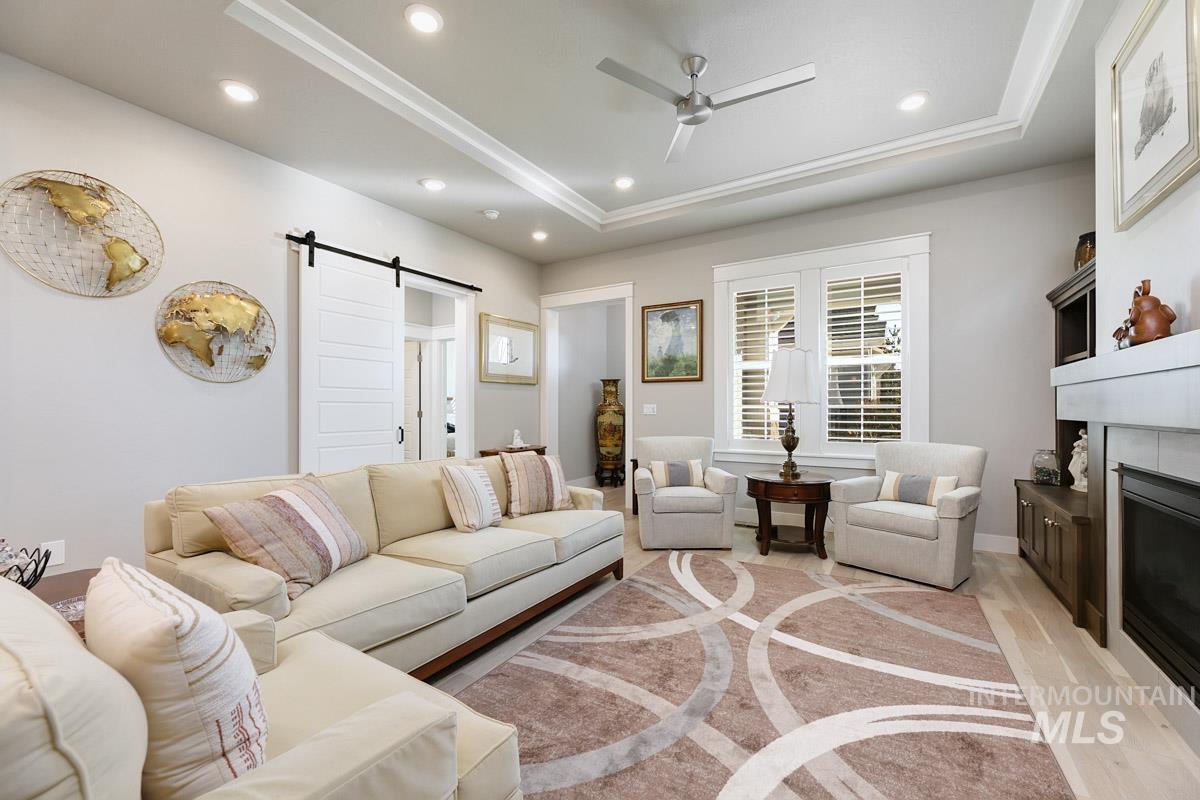 410 West Lockhart Lane Meridian, ID 83646 - Photo 8 of 41 Living area featuring a barn door, ceiling fan, a tray ceiling, a glass covered fireplace, and recessed lighting