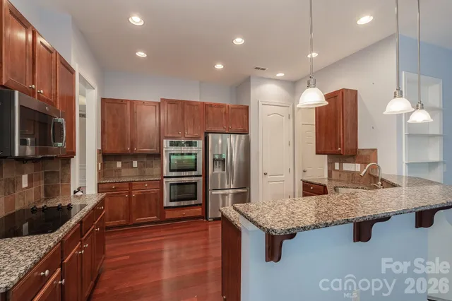 a kitchen with stainless steel appliances granite countertop a sink refrigerator and microwave