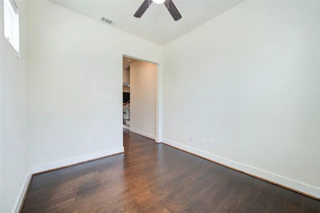 an empty room with ceiling fan and window