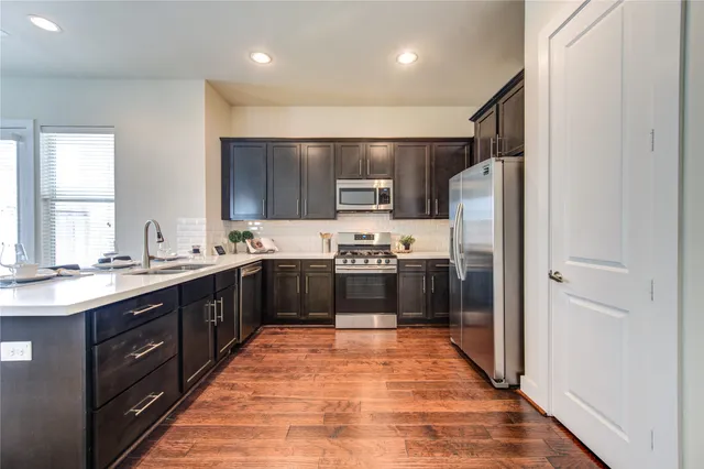 a large kitchen with stainless steel appliances a sink and a refrigerator