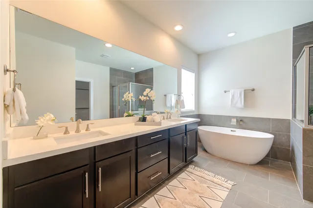 a spacious bathroom with a double vanity sink mirror and bathtub