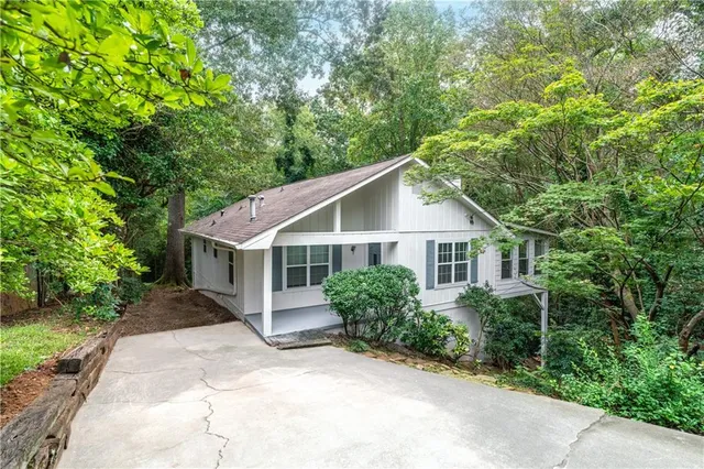 a view of a house with a yard and large trees