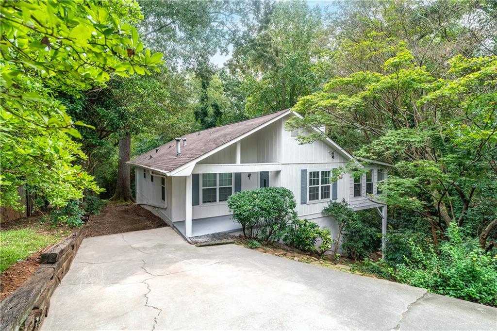 a view of a house with a yard and large trees