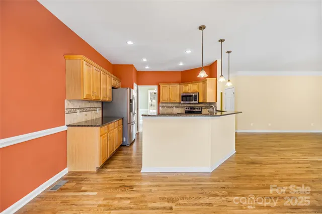 a kitchen with stainless steel appliances granite countertop a refrigerator a stove top oven and a sink