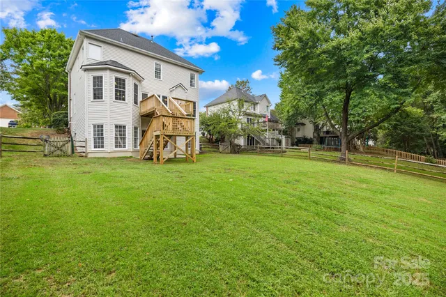 a view of a white house with a big yard and large trees