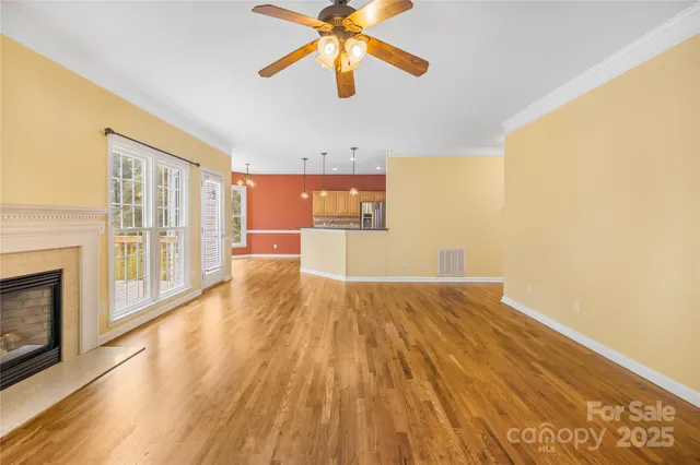 a view of empty room with wooden floor and fan