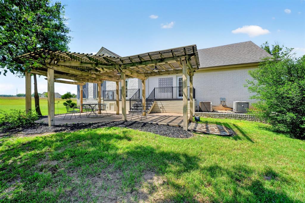 1901 Rose Pointe Athens, TX 75752 - Photo 28 of 37 Expansive outdoor patio featuring a wooden pergola, gravel ground cover, and a staircase leading to an upper-level deck with black railings