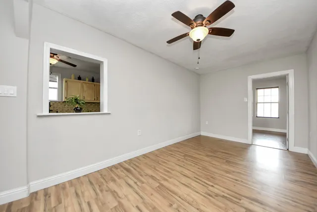 a view of an empty room with window and wooden floor