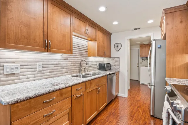 a kitchen with stainless steel appliances granite countertop a sink and wooden cabinets