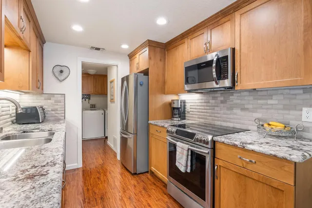 a kitchen with stainless steel appliances granite countertop a stove a sink and a refrigerator