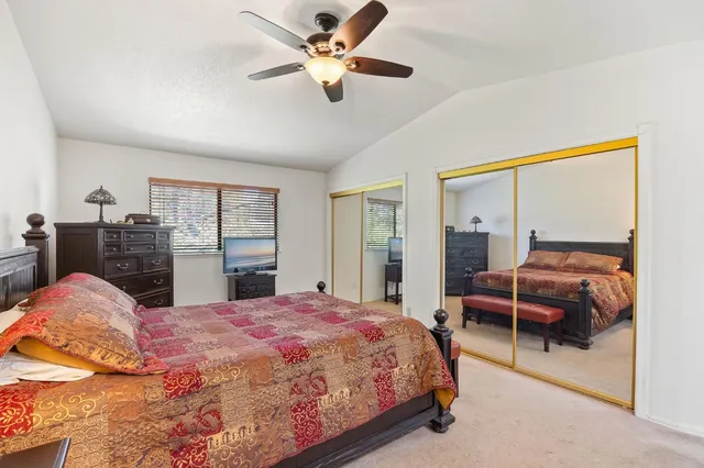 a bedroom with a large bed and a chandelier fan