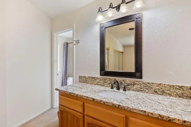 a bathroom with a granite countertop sink and a mirror