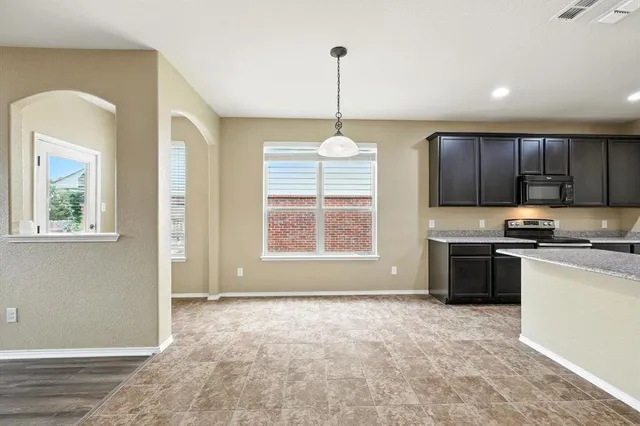 a kitchen with stainless steel appliances granite countertop a stove a sink dishwasher a refrigerator and a wooden floor