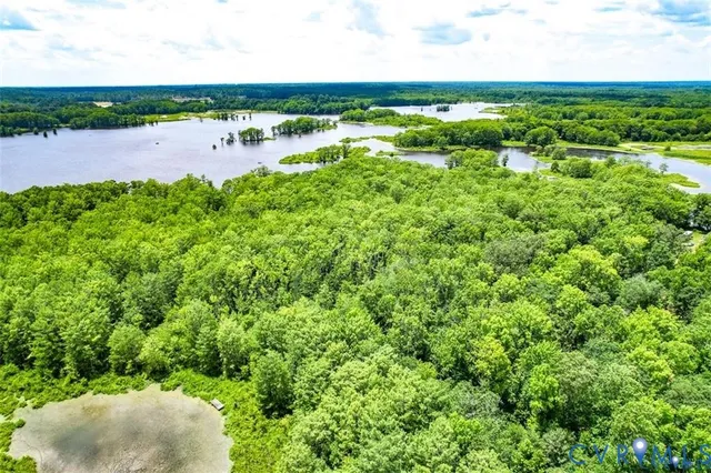 an aerial view of ocean with residential house with outdoor space and trees around