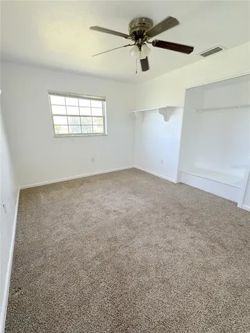 an empty room with windows and fan
