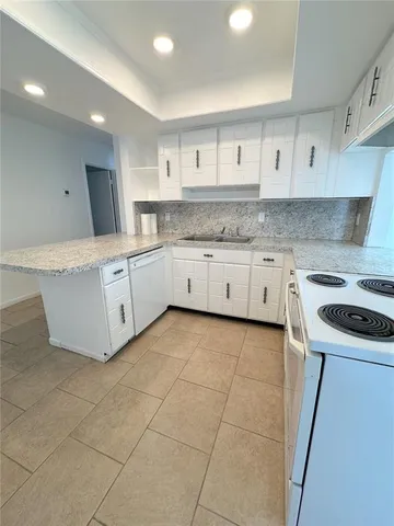 a kitchen with granite countertop a sink a stove top oven and cabinets
